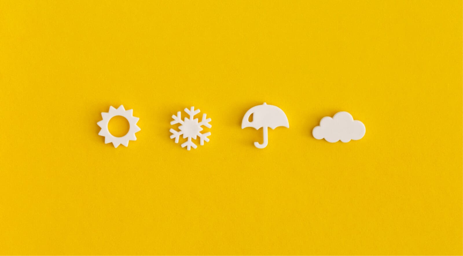 bright yellow background with four white 3-D icons of weather sun snowflake umbrella and cloud in straight horizontal line