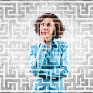 woman face on with one arm crossed and other chin staring at an opaque maze across entire image