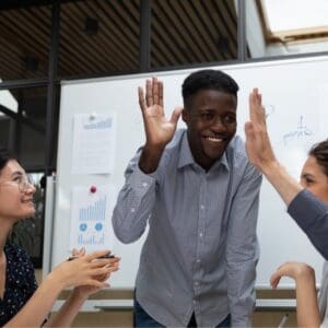 Corporate team meeting working on project using white board celebrating with smiles and high fives